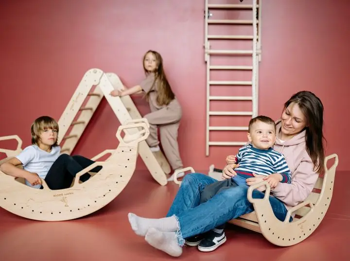 Children and mom enjoying fun indoor playtime on wooden climbing toys.