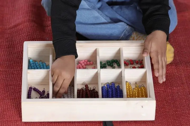 Child engaging with Montessori bead material for math learning.