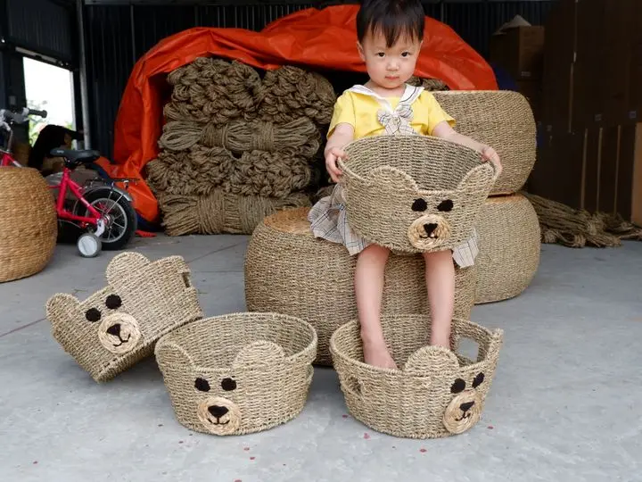 Cute child playing with handmade woven baskets indoors.