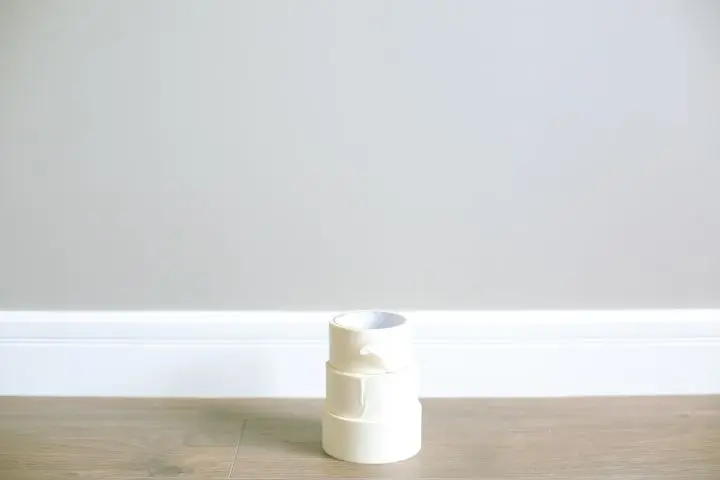 Stack of white masking tape on a wooden floor against a minimal interior wall.