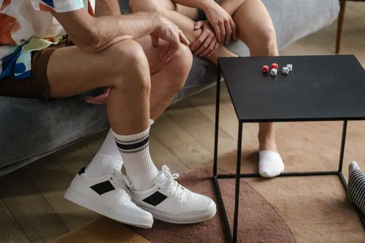 A couple sitting together playing a dice game on a black table indoors, casual atmosphere.