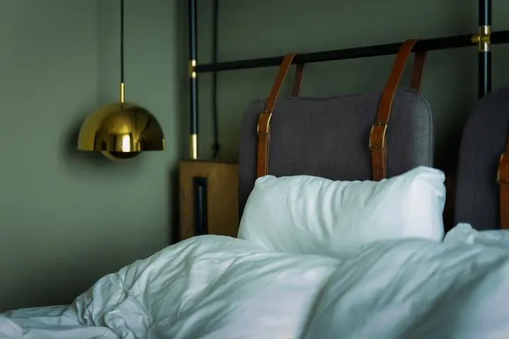 A cozy, modern bedroom interior with stylish lighting and luxurious bedding.