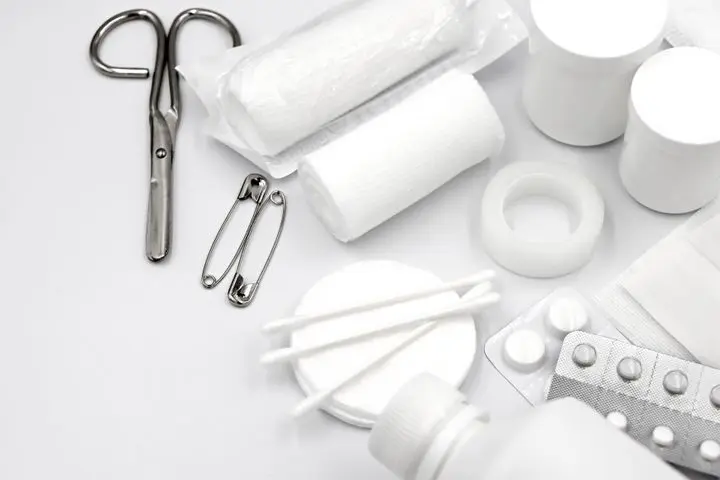 A detailed flat lay of essential first aid supplies including bandages, scissors, and pills.