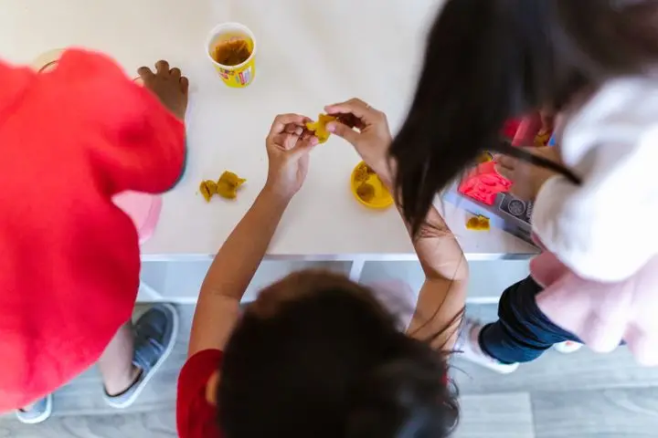 Overhead view of kids playing and learning with clay at a table.