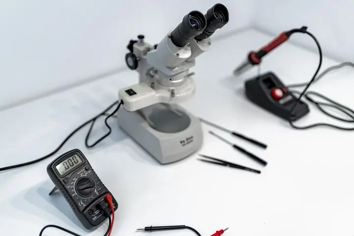 A laboratory workbench featuring a microscope, multimeter, and precision tools for scientific research.