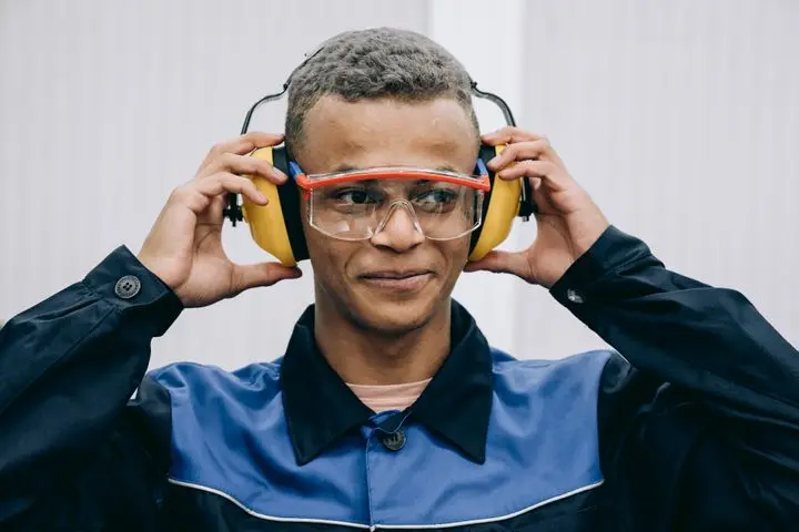 Confident worker adjusts safety gear, highlighting industrial safety practices.