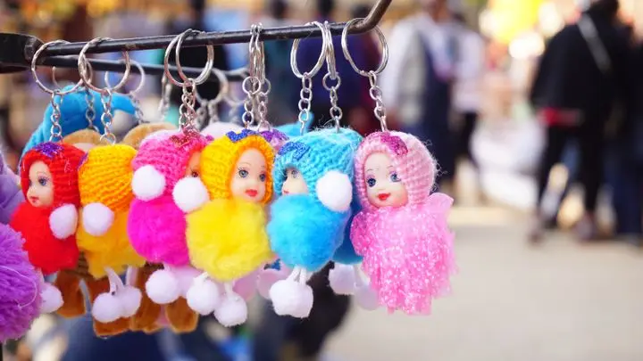 Vibrant knitted doll keychains hanging on a rack, perfect for decorative purposes.