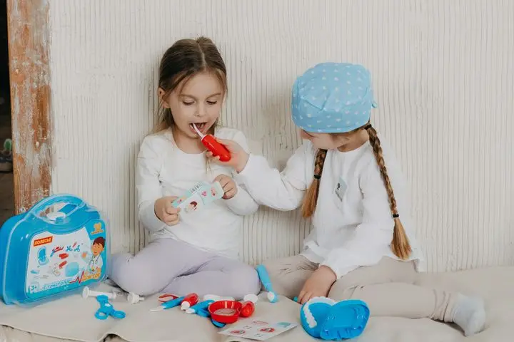 Two children playing dentist at home with a toy set, learning and having fun.