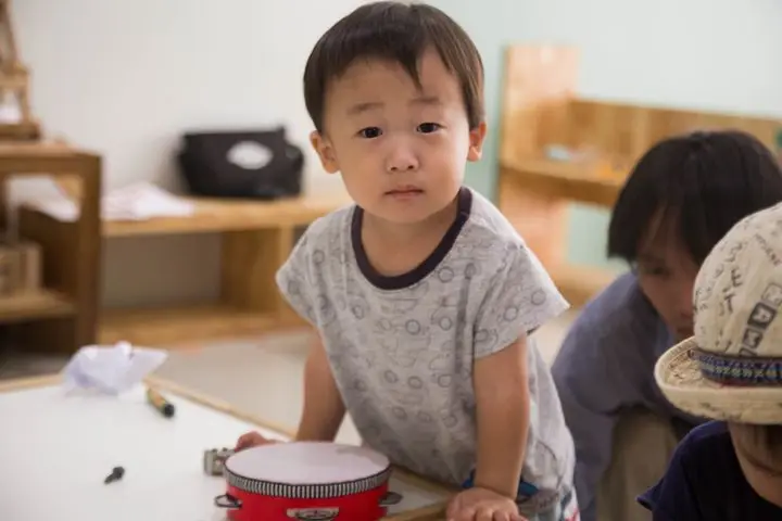 Adorable child exploring a toy drum, capturing curiosity in a cozy indoor setting.