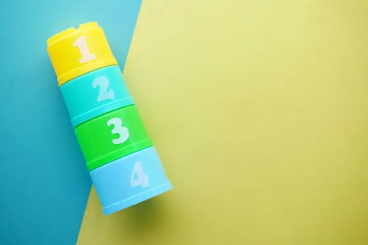 Bright, colorful numbering cups for educational play stacked on a vibrant multicolor background with ample copy space.