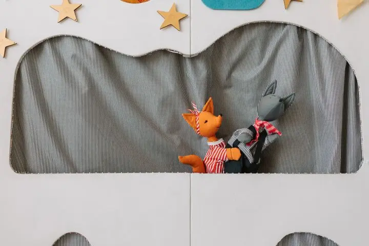 Bright puppet theater setup with two animal puppets performing on stage.